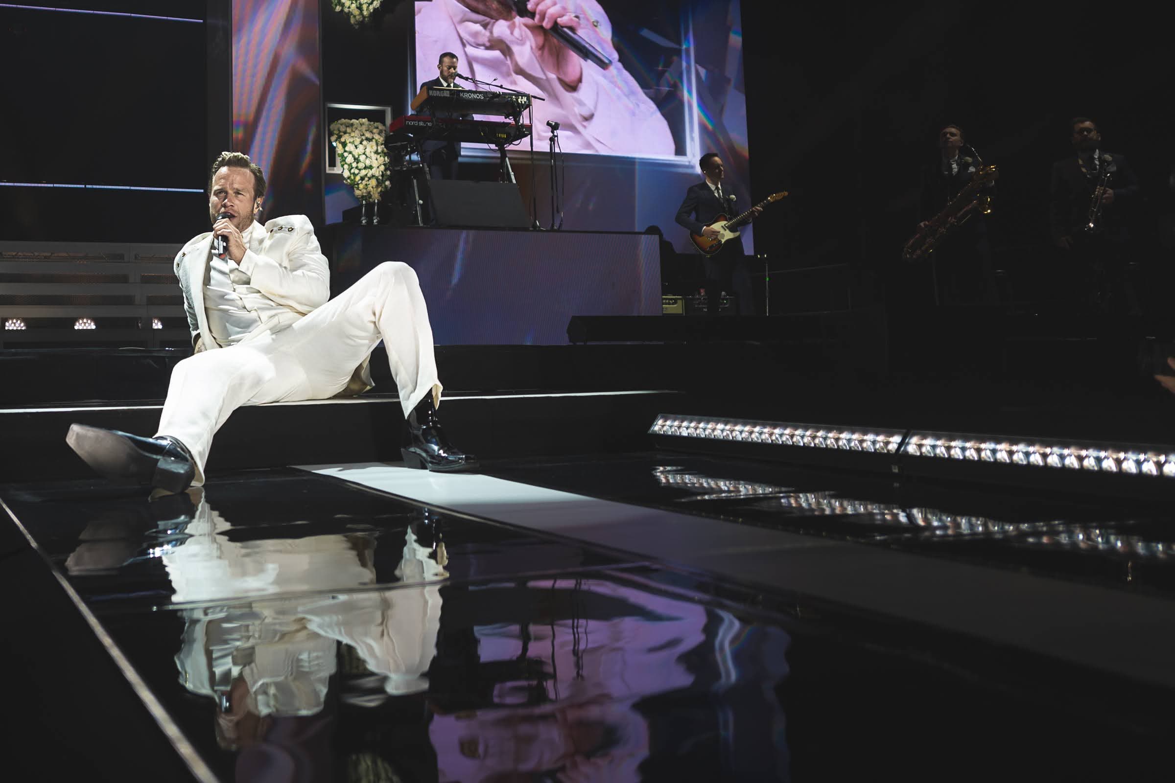 Olly Murs performing at AO Arena in Manchester with a reflection across the stage floor.