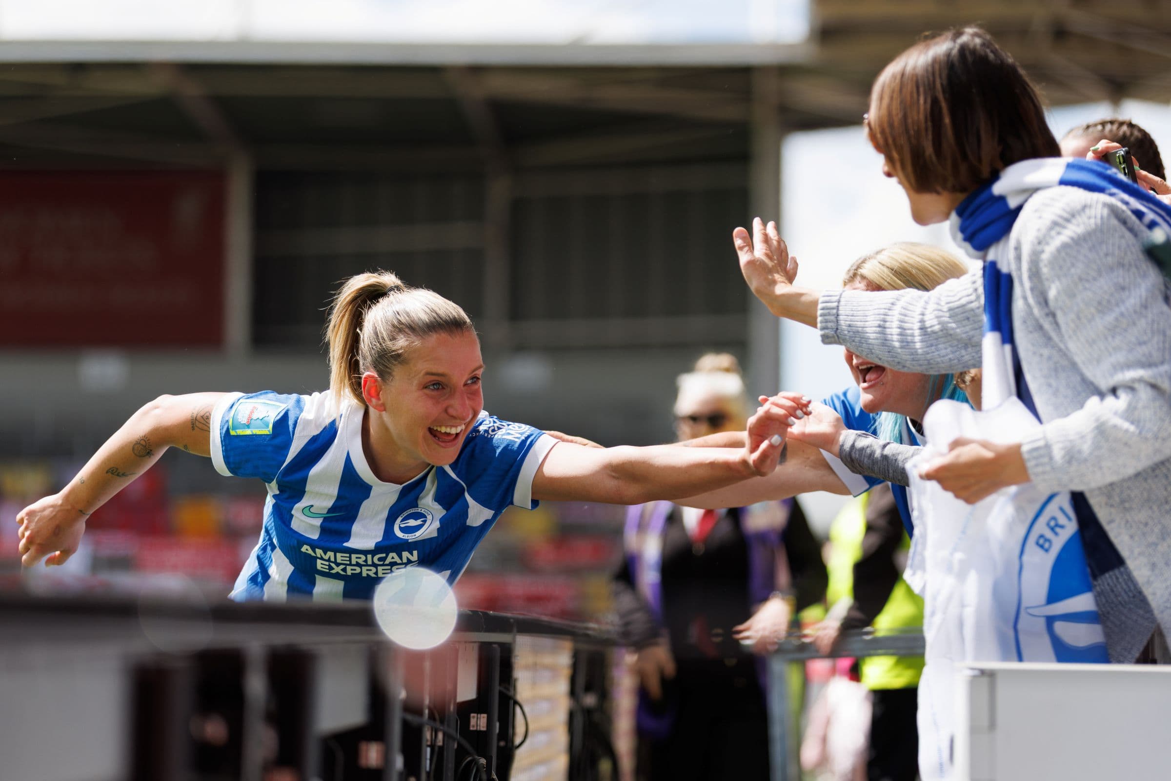 Footballer celebrating with supporters at the side of the pitch.