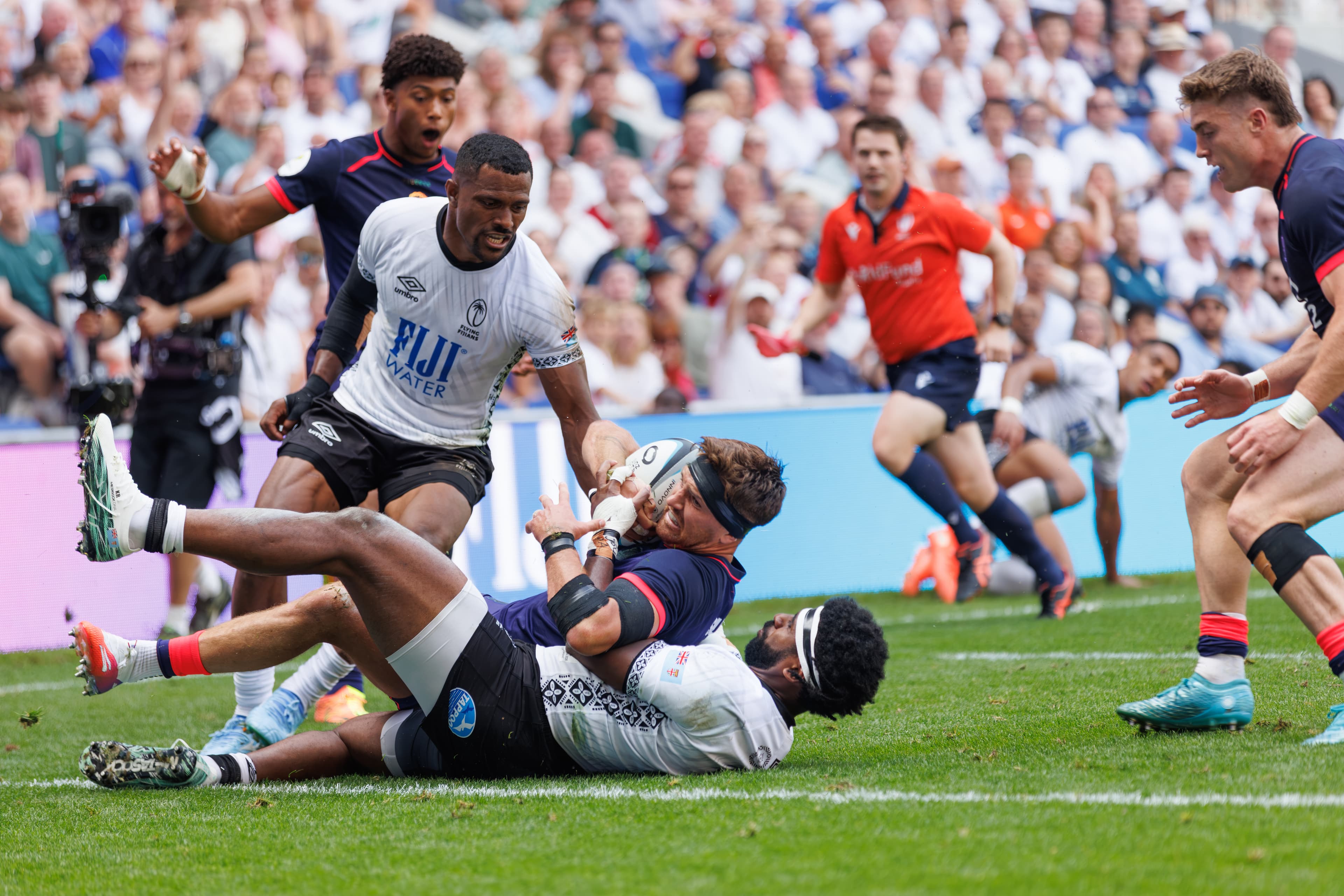 Fiji and England rugby players colliding in a tackle during open play.