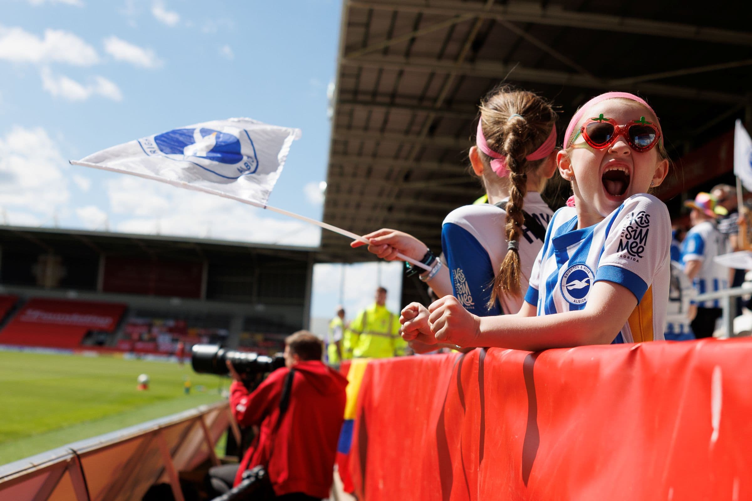 Football fans leaning over a barrier inside a stadium.