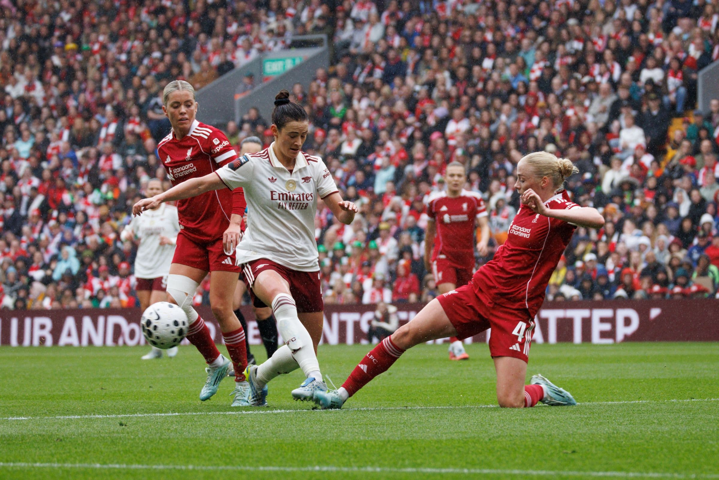 Footballer sliding into a tackle during a crowded live match.