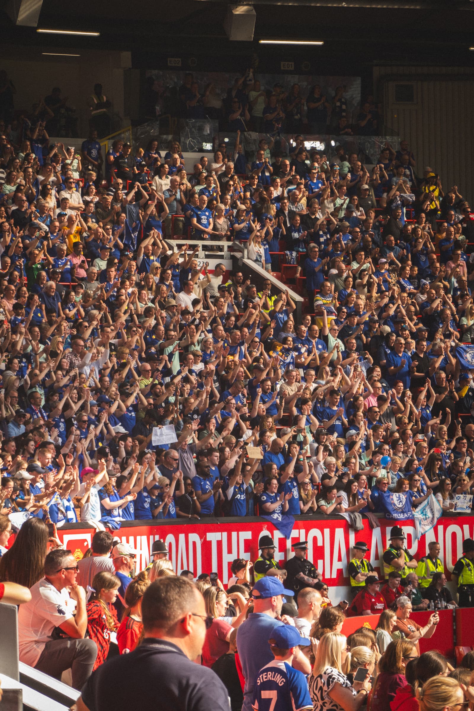 Packed football supporters filling a stadium stand during a live match.
