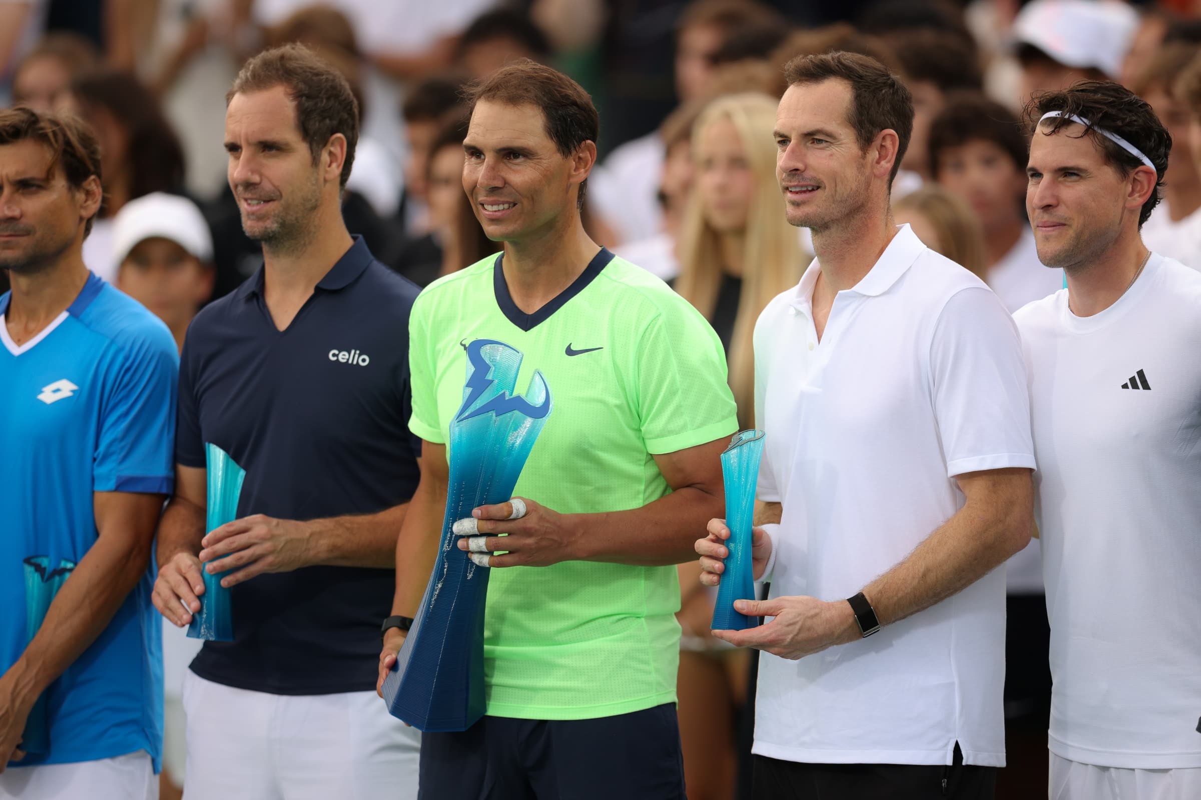 Rafael Nadal, Andy Murray, and other players standing together on court at the Rafa Nadal Academy Slam.